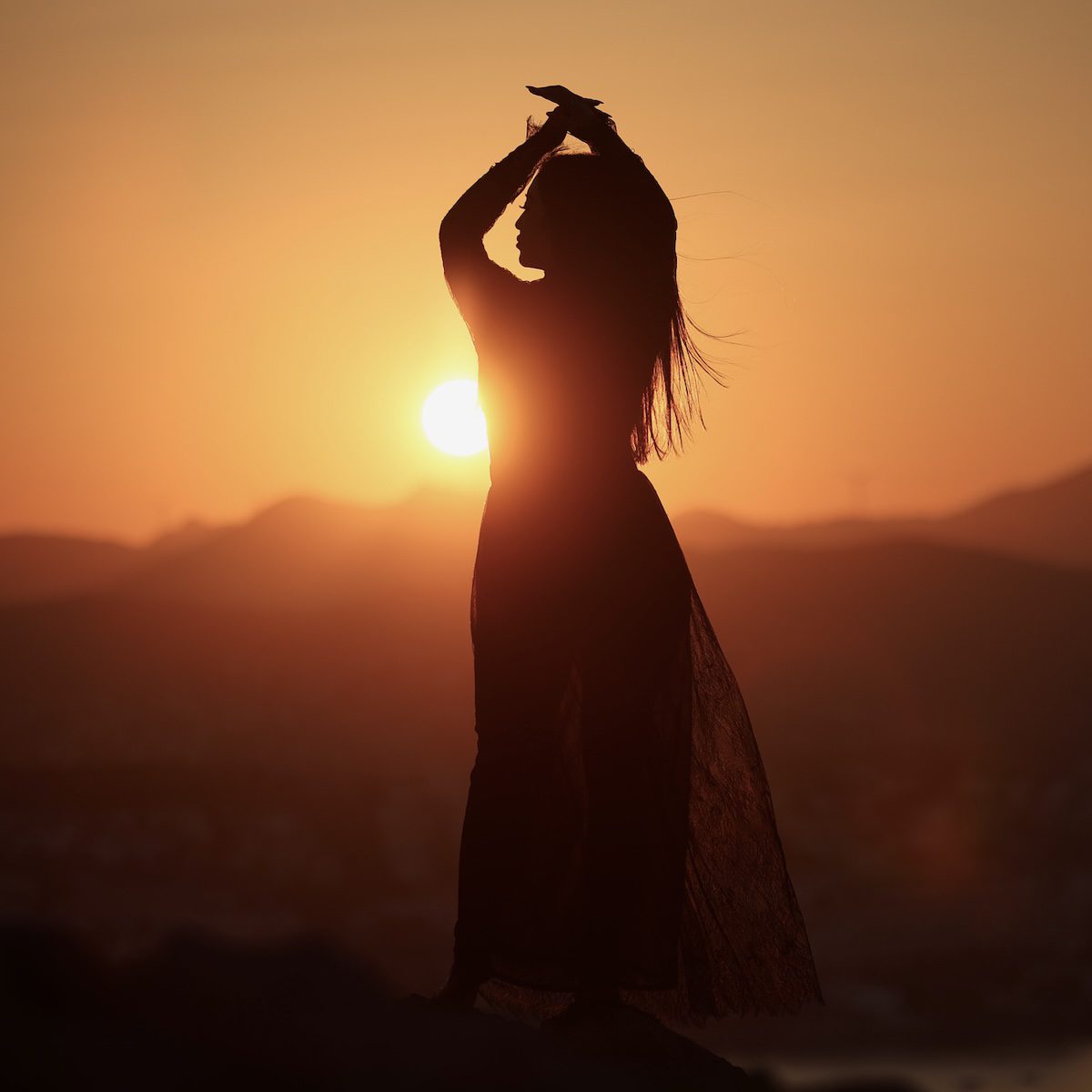 Joyful Asian woman. A joyful young Asian woman embraces the breathtaking beauty of a stunning sunset.