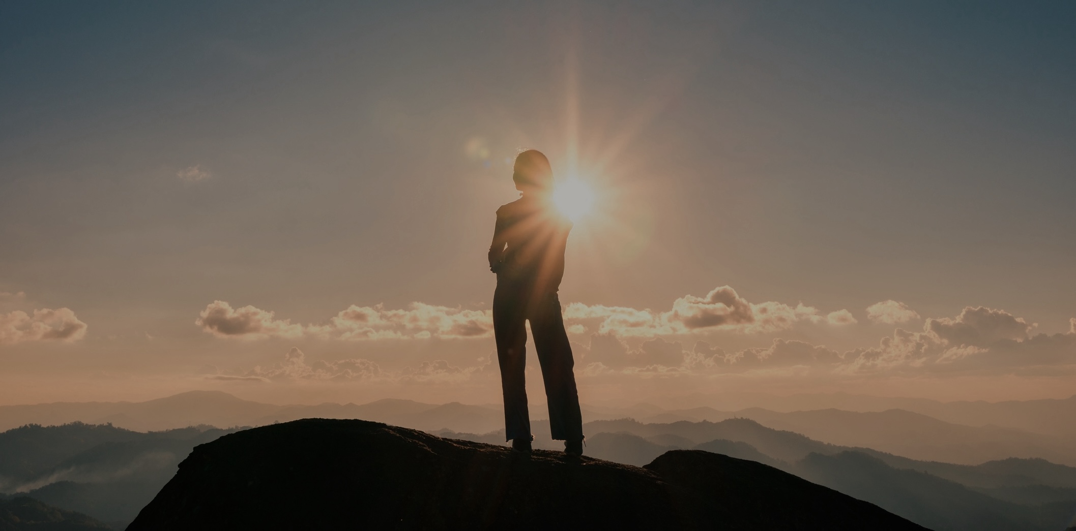 Successful silhouette young hiker woman standing on top of mountain peak in the sunset at national park