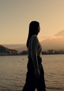 Woman, walking by river and nature with travel and journey outdoor, holiday or vacation with break. Environment, water and fresh air, traveller on adventure with peace, calm and wellness on trip
