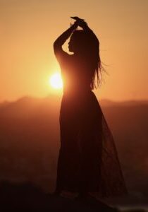 A joyful young Asian woman embraces the breathtaking beauty of a stunning sunset.